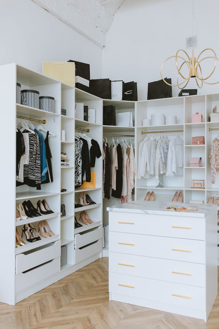 A stylish walk-in closet featuring luxury clothing, shoes, and accessories, with elegant shelving and chandeliers.
